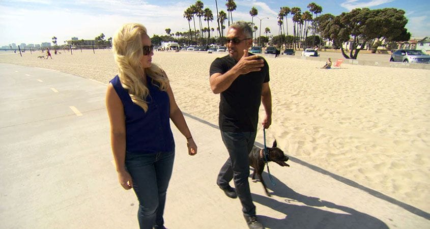 Cesar, a woman, and her dog walk on the beach