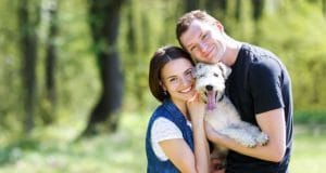 A couple and their adopted dog enjoy a nice walk in the park.