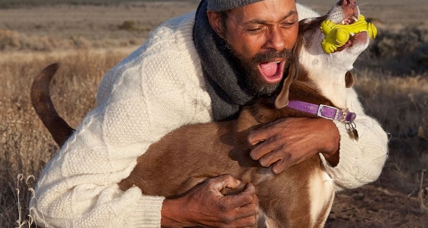 A man gives affection to his dog after a walk.